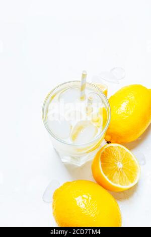 Sommerliches Erfrischungsgetränk, kaltes Wasser mit Eis und Zitrone, weißer Hintergrund, Draufsicht Stockfoto