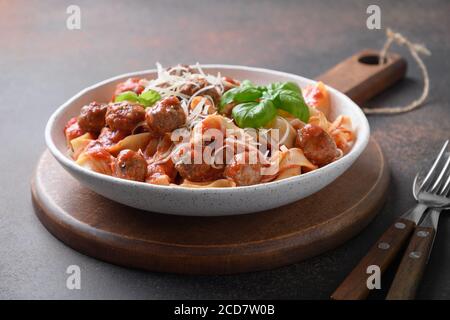 Pasta Fettuccine mit Fleischbällchen, Parmesan, Tomaten, Basilikum auf Braun. Nahaufnahme. Stockfoto