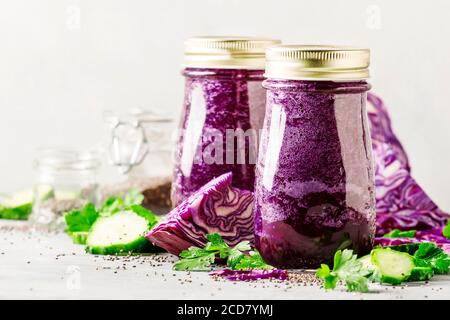 Gesunde vegane Detox Purple Smoothies oder Saft aus Rotkohl, Gurken mit Chiasamen in Glasflaschen auf grauem Hintergrund, selektiver Fokus Stockfoto