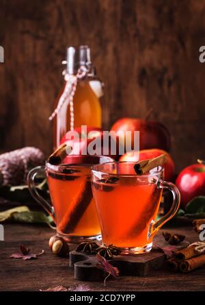 Heißer Apfelmost mit Zimtstangen, Nelken und Anis auf Holzgrund. Traditionelle Herbstgetränke, Wintergetränke und Cocktails Stockfoto