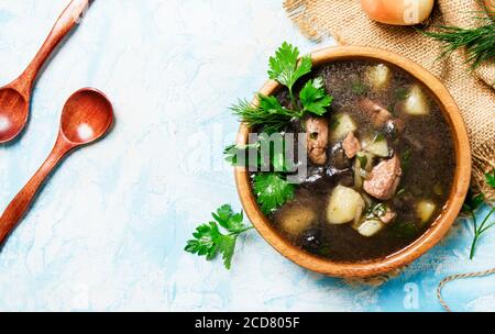 Hausgemachte Suppe mit Fleisch und Waldpilzen, blauer Stein Hintergrund, Draufsicht Stockfoto