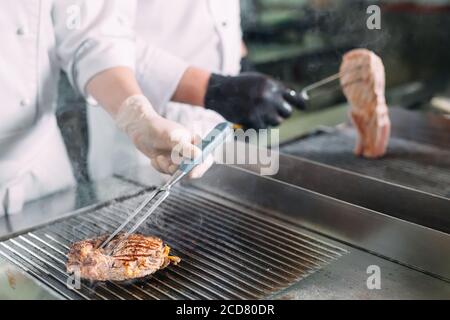 Kocht Braten Fleisch auf dem Herd in der Küche eines Restaurants oder Hotels. Stockfoto