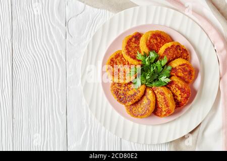 Gesunde vegane Butternut-Kürbiskuchen auf einem weißen Teller mit Petersilie auf weißem Holzhintergrund serviert, Draufsicht, Kopierraum, Nahaufnahme Stockfoto
