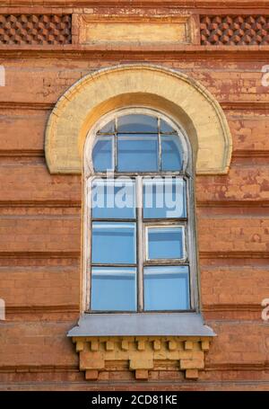 Altes Holzfenster in einem Ziegelgebäude. Rote Ziegelwand und Holzfensterrahmen. Stockfoto