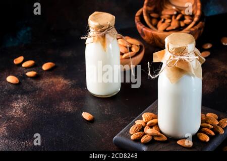 Vegane Mandelmilch in Flaschen, Nahaufnahme, brauner Hintergrund. Nicht milchfreie Alternativmilch. Gesundes vegetarisches Essen und Trinken Konzept. Speicherplatz kopieren Stockfoto