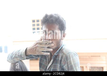 jodhpur, rajasthan, indien, 20. September 2020: Armer indischer Arbeiter Rauchen Zigarette Blick auf die Kamera, tagsüber, Arbeitslosigkeit. Stockfoto