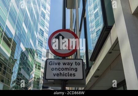 Geben Sie Platz zu entgegenkommenden Fahrzeugen Schild mit den Büros der City of London hinter. Stockfoto