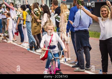 Kind auf dem Fahrrad und Menschen mit Blumen bei friedlichen Protesten gegen gestohlene Präsidentschaftswahlen in Minsk, Weißrussland. Minsk, Weißrussland - Augus Stockfoto