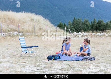 Zwei Mädchen mit einem Picknick auf dem Berg und die Kleines Mädchen trinkt Wasser Stockfoto