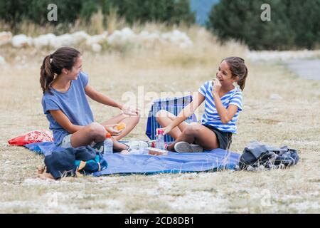 Zwei Mädchen sitzen Spaß auf dem Berg, während mit Ein Snack Stockfoto