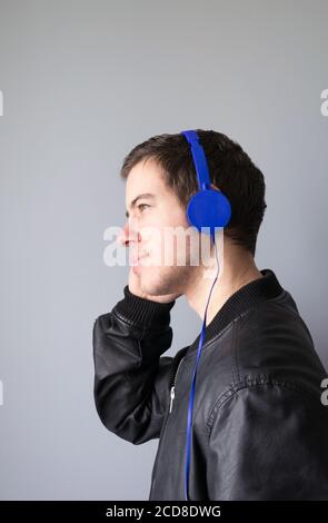 Eine Seitenansicht eines Teenagers, der mit Musik hört Blauer Kopfhörer Stockfoto