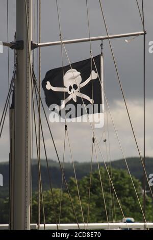 Ein Schädel und Kreuzknochen, der fröhliche roger, Flagge, die in der Takelage einer Yacht in einem Schloss auf dem Crinan Canal, Argyll, Schottland fliegt Stockfoto