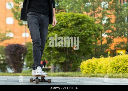 Stilvoller Mann Skateboarder Reiten Longboard in der Stadt, im Freien, abgeschnitten Bild. Freizeit, gesunder Lebensstil, Extremsport Stockfoto