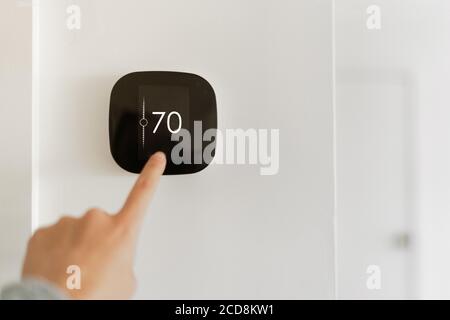 Thermostat Indoor Smart Home in House System für Temperatur. Winter Heizung energieeffiziente Automatisierung digitale Touchscreen Wand Hand berühren Gerät Stockfoto