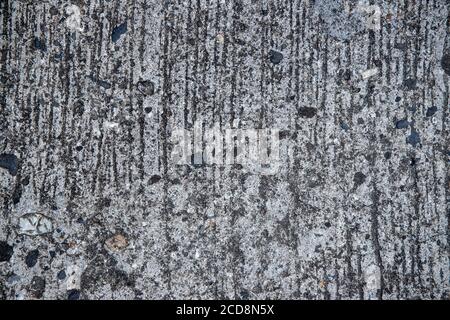 Verwitterte zerkratzte Betonoberfläche Fototextur. Grunge Betonstraße Blick von oben. Raue Beton- oder Asphaltfläche mit Kies. Alte grungige Straße Text Stockfoto