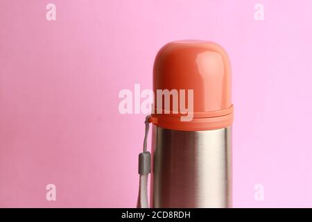 Nahaufnahme einer orangefarbenen Thermoskanne isoliert auf einem rosa Hintergrund Stockfoto