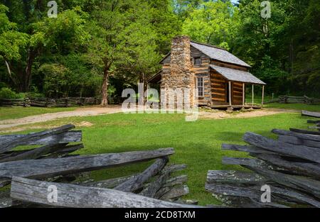 Frühes Siedlergehöft mit Steinkamin und umgebenen Holzzaun und schönen Bäumen im Sommer in der Nähe von Gatlinburg, Tennessee, USA. Stockfoto