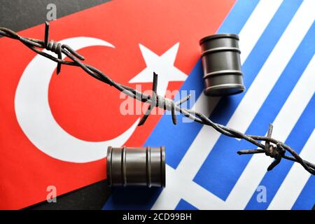 Die Flaggen der Türkei und Griechenland und Ölfässer hinter Barbwire, Ägäis Streit Stockfoto