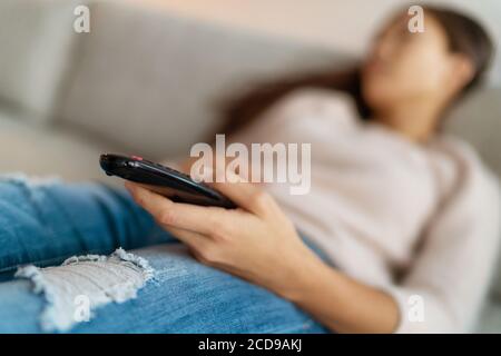 Fernsehen langweilen Frau müde Einschlafen mit Fernbedienung in der Hand sitzen auf dem Sofa zu Hause allein. Single Lifestyle Langeweile Stockfoto