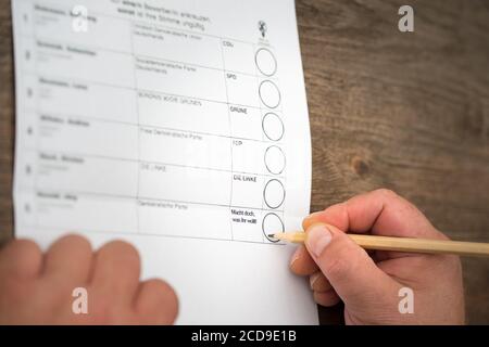 Brilon, Nordrhein-Westfalen/ Deutschland: 27. August 2020: Ein Mann sitzt vor einer Wahlurne für die Wahl. Deutscher Parteiname und ein fiktiver Deutscher Stockfoto