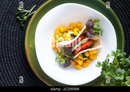 Gesundes Lebensmittelkonzept Veganer mikrogrüner Salat Tacos Sandwich in weiß Keramikschale auf schwarz matt mit Kopierfläche Stockfoto