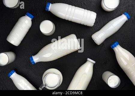 Milchprodukte Verpackung, Flaschen und Gläser mit Milch auf schwarzem Hintergrund, Draufsicht Stockfoto