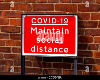 Ein rotes Straßenschild Covid 19 halten soziale Distanz Stockfoto