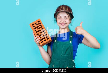 Beste Qualität. Glückliche Kindheit. Kid tragen Schutzhelm. Schützen Kopf auf Baustelle. Teen Mädchen halten Ziegel. Kleine Baumeister mit Ziegel. Kind ist Ingenieur Architekt. Bauen ihr zukünftiges Haus. Stockfoto