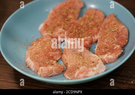 Nahaufnahme von rohen Schweinekoteletts mit verschiedenen Gewürzen auf Eine Platte Stockfoto