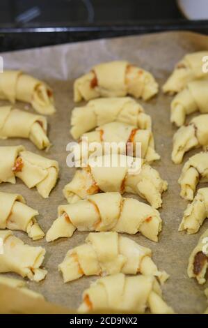 Vertikale Aufnahme von ungekochten Kifli Kekse mit Marmelade gefüllt auf Pergamentpapier Stockfoto