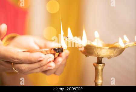 Nahaufnahme der Frau Hände Beleuchtung Öl Laterne oder Diya während der Festfeier - Konzept der traditionellen indischen Festival und rituelle Feiern. Stockfoto