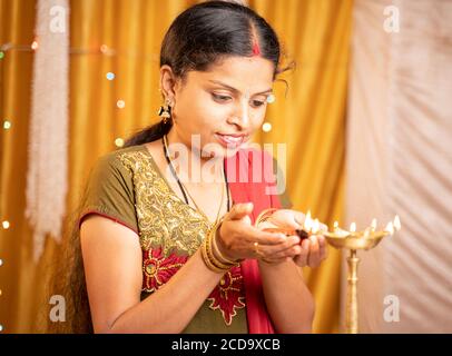 Happy Smiling Indian Frau Beleuchtung Laterne oder Diya Lampe während der Festfeier zu Hause - Konzept der traditionellen Festival-und rituelle Feiern. Stockfoto