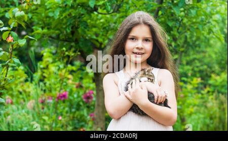 Kleines Mädchen spielen mit niedlichen Kätzchen Katze Natur Hintergrund, verspielte Kind Konzept. Stockfoto