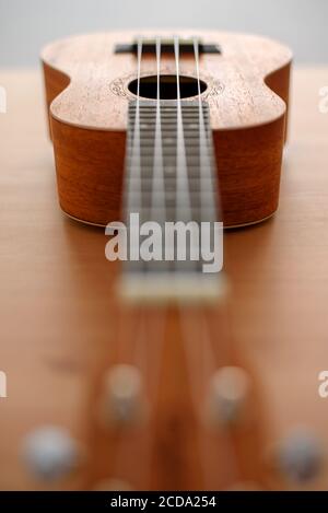 Nahaufnahme einer braunen Ukulele auf hölzernem Hintergrund mit sehr Flache Tiefe des Feldes Stockfoto