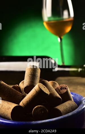 Korken auf einer Schüssel, mit einer Flasche und einem Glas Wein im Hintergrund, Studioaufnahme Stockfoto