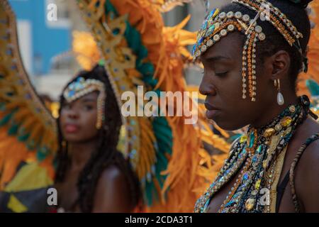 Weibliche Teilnehmerin in einem schönen Kostüm in Gedanken verloren vor dem Beginn der Notting Hill Carnival 2019 Parade gesehen. Stockfoto