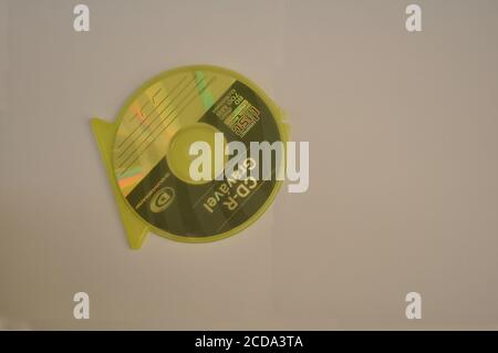 Compact Disc für die Aufzeichnung von Daten in gelber Kunststoffabdeckung in Fischform Draufsicht auf weißem Hintergrund Stockfoto