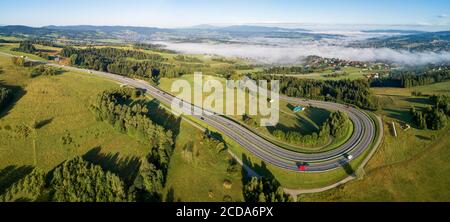 Polen. Breites Panorama einer kurvenreichen Rückstraße von Krakau nach Zakopane, genannt Zakopianka, in der Nähe von Rabka und Chabowka. Luftaufnahme im Sonnenaufgangslicht w Stockfoto