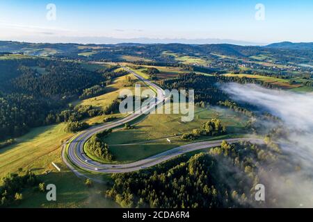 Polen. Kurvenreiche Rückweg von Krakau nach Zakopane, genannt Zakopianka, in der Nähe von Rabka und Chabowka. Luftaufnahme im Sonnenaufgangslicht mit Morgennebel. Fa Stockfoto