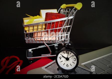 Black friday Konzept auf schwarzem Hintergrund. Bunte Geschenktaschen, Warenkorb, Kreditkarte, Computer Stockfoto