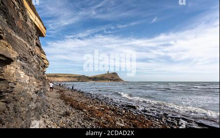 Kimmeridge Bay mit felsiger Uferlinie und Fossilienjägern, mit dem Clavell Tower im Hintergrund in Kimmeridge, Isle of Purbeck, Dorset, UK am 26. Aug Stockfoto