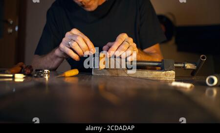 Mann näht Lederdetails in Schraubstock geklemmt. Handwerker arbeitet mit Nadel und Faden. Small Business-Konzept mit Platz für Text. Stockfoto