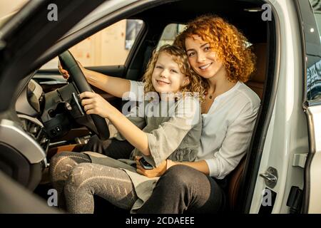 Junge kaukasische Besitzer von neuen Automobil. Mutter und Tochter kamen, um neues Auto in Händler zu bekommen, sie bekam Schlüssel von ihm. Glück Stockfoto