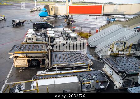 Gepäckwagen und andere Ausrüstung zum Be- und Entladen von Flugzeugen Auf dem Asphalt eines Flughafens Stockfoto