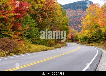 Atemberaubende Herbstfarben entlang einer verlassenen, gewundenen Bergstraße Stockfoto