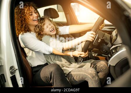 Positive kaukasische Frau und Kind Mädchen in Händler, sie bekam Schlüssel aus dem neuen Auto. Neue Besitzer glänzen mit Glück Stockfoto