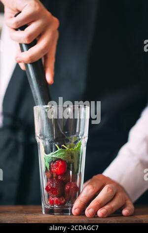 Der Barkeeper bereitet auf der Terrasse des Restaurants einen Beerencocktail zu. Stockfoto