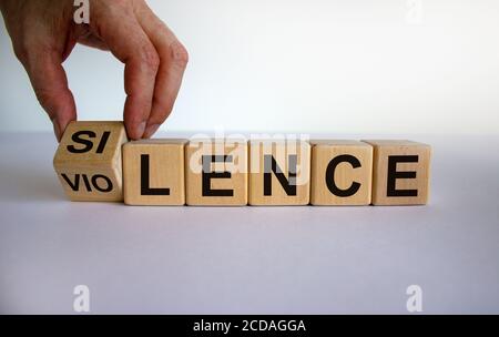 Hand dreht einen Würfel und ändert das Wort "Silence" in "Gewalt" oder umgekehrt. Schöner weißer Hintergrund, Kopierbereich. Business und Social concep Stockfoto