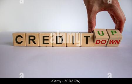 Hand dreht Würfel und ändert den Ausdruck 'Credit down' in 'Credit up'. Schöner weißer Hintergrund. Geschäftskonzept, Kopierbereich. Stockfoto