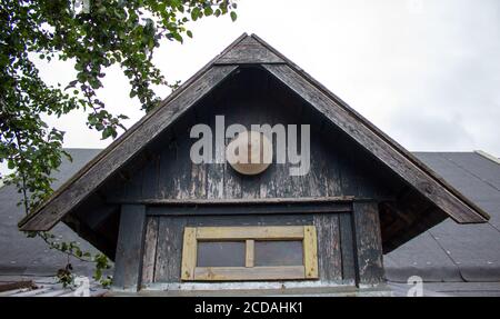 Alte Erweiterungen auf dem Dach eines alten Gebäudes aus Brettern und Baumstämmen auf dem Land, Nahaufnahme gegen den Himmel. Stockfoto